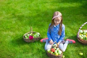 aanbiddelijk weinig meisje met herfst oogst van tomaten in manden foto