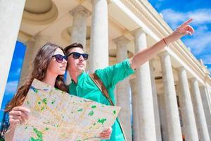 jong toerist vrienden op reis Aan vakantie in Europa glimlachen gelukkig. Kaukasisch familie met stad kaart in zoeken van attracties foto
