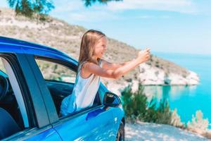 weinig meisje Aan vakantie reizen door auto. zomer vakantie en auto reizen concept foto