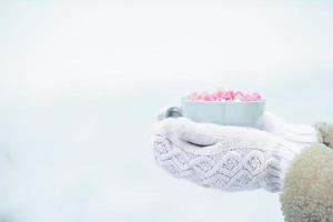 vrouw handen vasthouden wit kop van koffie met wit en roze marshmallows foto