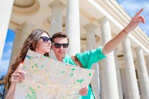 jong toerist vrienden op reis Aan vakantie in Europa glimlachen gelukkig. Kaukasisch familie met stad kaart in zoeken van attracties foto