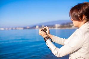 vrouw handen Holding klein stenen het formulier hart vorm achtergrond de zee foto