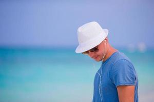 jong Mens genieten van de muziek- Aan wit zanderig strand. gelukkig toerist ontspannende Aan zomer tropisch vakantie. foto