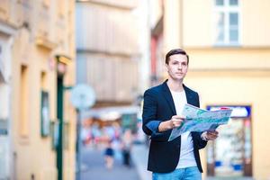 Mens toerist met een stad kaart in Europa. jong vent op zoek Bij de kaart van Europese stad in zoeken van attracties. foto