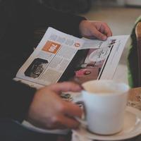 persoon die leest terwijl hij witte keramische mok vasthoudt foto