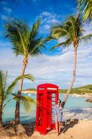 mooi vrouw in de buurt rood telefoon stand in van Dickenson baai antigua. foto