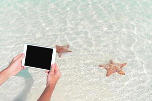 detailopname laptop Aan de achtergrond van turkoois oceaan Bij tropisch strand nemen een foto van zeester in natuurlijk reserveren