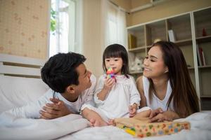 gelukkig kind met ouders die thuis spelen foto