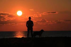 silhouet van mens en hond bij zonsondergang