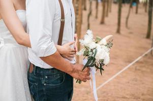 detailopname brug en bruidegom staand en omarmen met Holding boeket bloem in de Woud Aan pre bruiloft dag foto