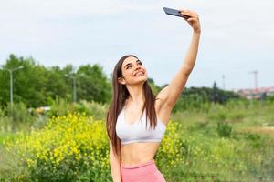 geschiktheid selfie vrouw zelf portret na training. sport atleet nemen selfies foto na werken uit rennen en opleiding buitenshuis. fit vrouw Kaukasisch sport model- glimlachen gelukkig.