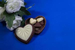 chocola bonbons met hart vormen en wit rozen foto