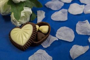 chocola bonbons met hart vormen en wit rozen foto