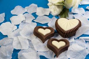 chocola bonbons Aan wit en roze roos bloemblaadjes foto