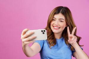 portret van gelukkig glimlachen jong vrouw vervelend gewoontjes t-shirt selfie met smartphone geïsoleerd over- roze achtergrond foto