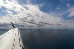 vliegtuig vleugel terwijl landen vliegend over- de zee achtergrond foto