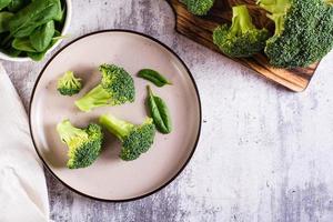 vers broccoli verdeeld in bloeiwijzen Aan een bord Aan de tafel. groente eetpatroon. top visie foto