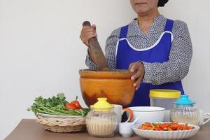 detailopname senior vrouw is Koken, slijtage schort, houdt stamper, Mortier. concept, Koken voor familie. Thais keuken levensstijl. ouderen werkzaamheid. foto