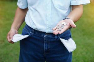 detailopname Mens draagt jeans, draaien uit zakken naar tonen leeg zak. maken handen gebaar naar tonen weinig munten geld. concept, economisch crisis. financieel problemen. kapot gegaan Bij de einde van maand. verloren geld. foto