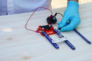 dichtbij omhoog handen slijtage blauw handschoenen demonstreren wetenschap experiment over elektriciteit circuit. concept, wetenschappelijk gereedschap voor opleiding, laboratorium les. aan het leren door aan het doen. foto