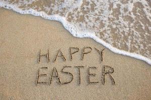 gelukkig Pasen geschreven Aan zanderig strand zee. top visie. foto