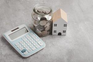 model- van een houten huis, munt rekenmachine. concept van besparing geld voor een toekomst huis. foto