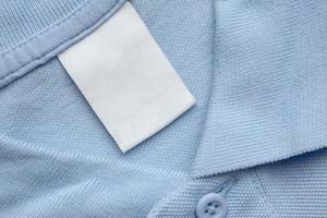 wit blanco wasserij zorg kleren etiket Aan blauw overhemd kleding stof achtergrond foto