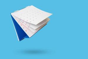wit papier bureau kalender flippen bladzijde geïsoleerd Aan blauw achtergrond foto