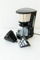 automatisch druppelen koffie maker geïsoleerd Aan wit tafel. zwart modern druppelen koffie pot. elektrisch keuken klein huishouden huishoudelijke apparaten. huishoudelijke apparaten. foto