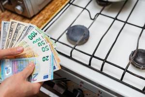 betaling van nut rekeningen, berekeningen Aan een rekenmachine. euro en dollar rekeningen liggen in de buurt een brandend gas- brander. de concept van toenemend de kosten van natuurlijk gas- levering en betaling. energie crisis foto