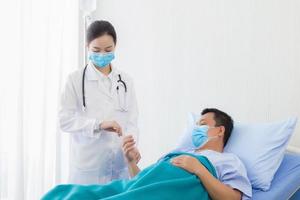 een Aziatisch vrouw dokter is nemen de pulse Aan de pols van een Mens geduldig foto