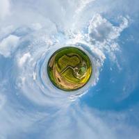 groene kleine planeet in blauwe lucht met prachtige wolken. transformatie van bolvormig panorama 360 graden. sferische abstracte luchtfoto. kromming van de ruimte. foto