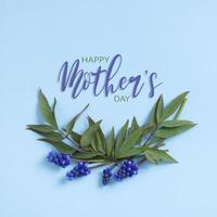 gelukkig moeders dag groet kaart met muscari bloemen anp pioniers bladeren Aan blauw achtergrond foto