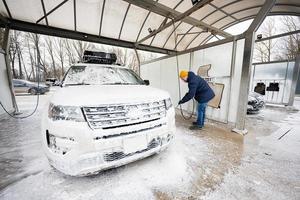 Mens het wassen hoog druk water Amerikaans suv auto met dak rek Bij zelf onderhoud wassen in verkoudheid het weer. foto