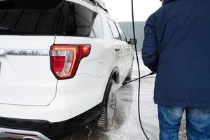 Mens het wassen hoog druk water Amerikaans suv auto Bij zelf onderhoud wassen in verkoudheid het weer. foto