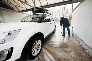 Mens het wassen hoog druk water Amerikaans suv auto met dak rek Bij zelf onderhoud wassen in verkoudheid het weer. foto