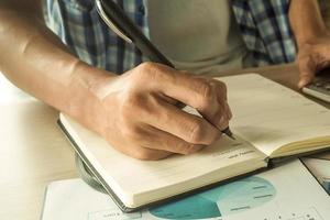 hand- geschreven naar de boek concept. Mens hand- vangst pen nemen aantekeningen Aan de boek. foto