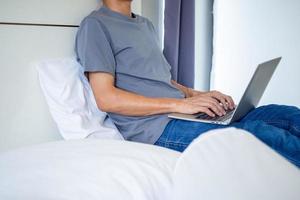 Mens typen of sociaal babbelen gebruik makend van computer Aan bed in de slaapkamer. mensen hebben netwerken dat genieten nieuw technologie - concepten van de nieuw generatie en sociaal media. blijven huis en sociaal afstand opslaan. foto