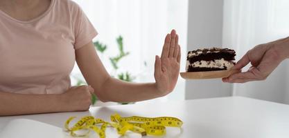 mager Dames weigeren naar eten chocola taart. Dames Doen niet eten trans vetten en suiker. eetpatroon concept foto