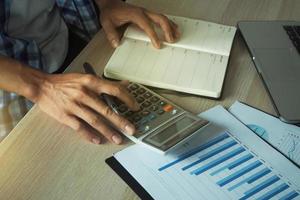 accounting concept Mannen hand- toepassingen een rekenmachine naar berekenen statistieken. over zijn werk berekenen de gegevens in de functie. foto