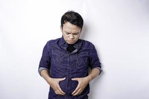 een portret van onzeker Aziatisch dik Mens is Holding de dik Aan zijn buik foto
