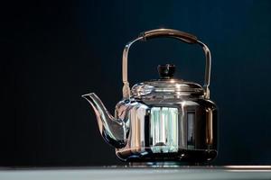 roestvrij water kraai of wijnoogst waterkoker thee pot Aan elektronisch fornuis in modern donker blauw achtergrond. foto
