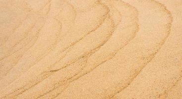 zand structuur achtergrond.top visie zanderig strand, natuurlijk zand steen structuur met golf, kust visie van bruin strand zand duin in zonnig dag lente, breed horizon voor zomer banier backdrop achtergrond foto