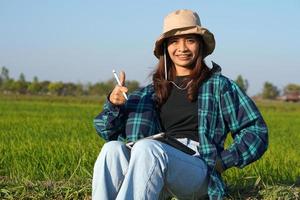 Aziatisch vrouw boeren gebruik computers naar analyseren de groei van rijst- planten. foto