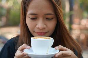 Aziatisch vrouw inademen aromatisch koffie foto