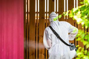 professioneel technisch Mens in het voorkomen pak met zijn steriliseren machine en desinfecteren water sprays in de buitenshuis veld- voor zuiverend coronavirus covid19. foto