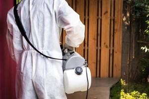 professioneel technisch Mens in het voorkomen pak met zijn steriliseren machine en desinfecteren water sprays in de buitenshuis veld- voor zuiverend coronavirus foto