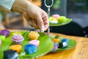 Thais chef-kok hand- is decoreren variëteiten traditioneel kleurrijk Thais desserts reeks stomen meel, zwart vla, kokosnoot vla en stomen Boon, laag pudding taart foto