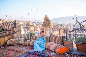 gelukkig jong vrouw gedurende zonsopkomst aan het kijken heet lucht ballonnen in Cappadocië, kalkoen foto