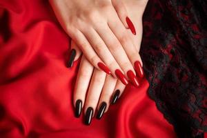 handen van een jong meisje met zwart en rood manicure Aan nagels foto